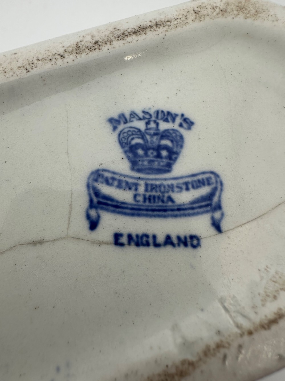 An antique oval ironstone jardiniere featuring blue and white transfer-printed Chinoiserie landscape decoration and small side handles with gilded detailing. View VII
