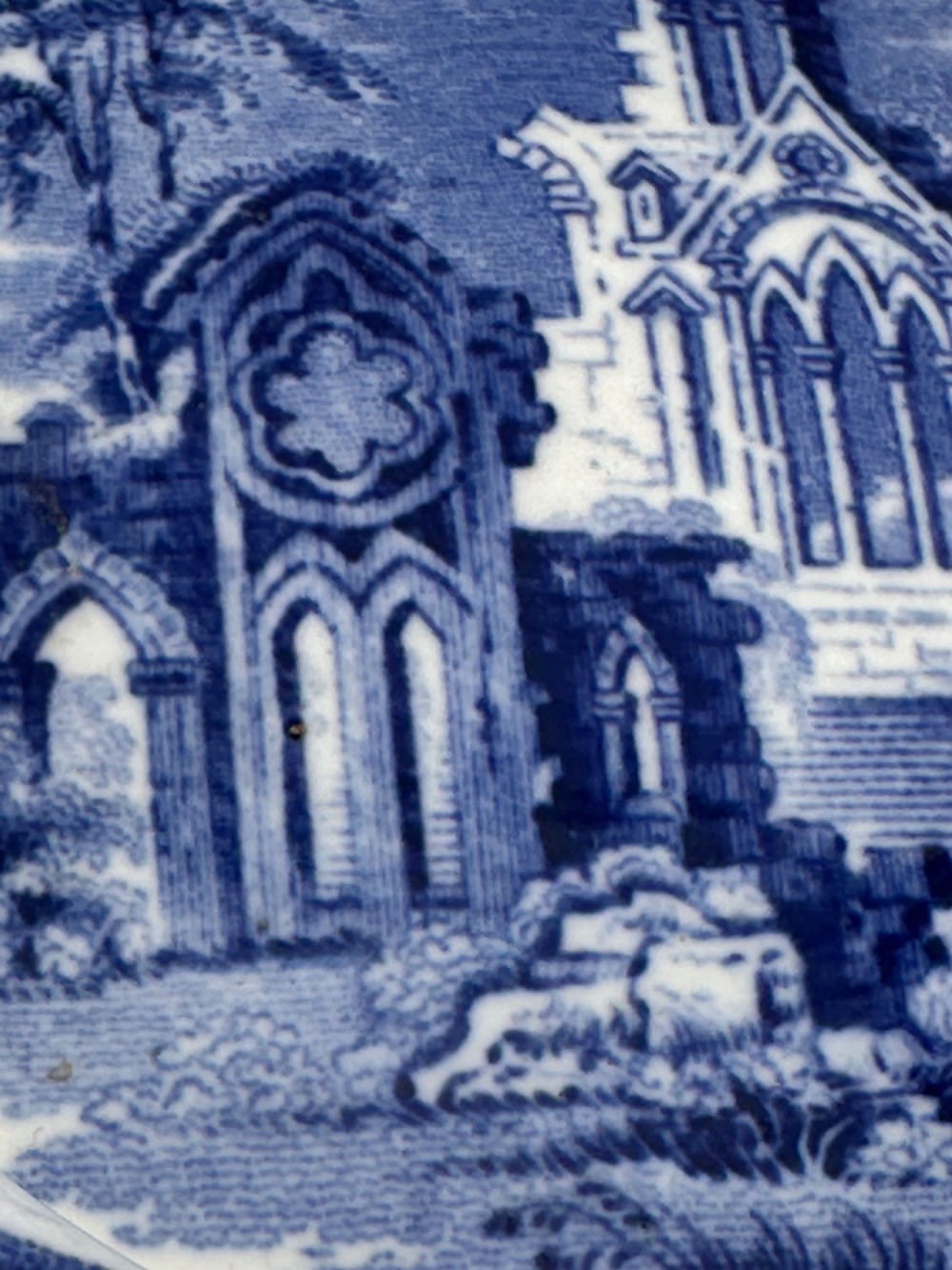 A circular blue and white transferware ceramic dish featuring a central printed depiction of abbey ruins framed by a decorative scrolled border. View VIII