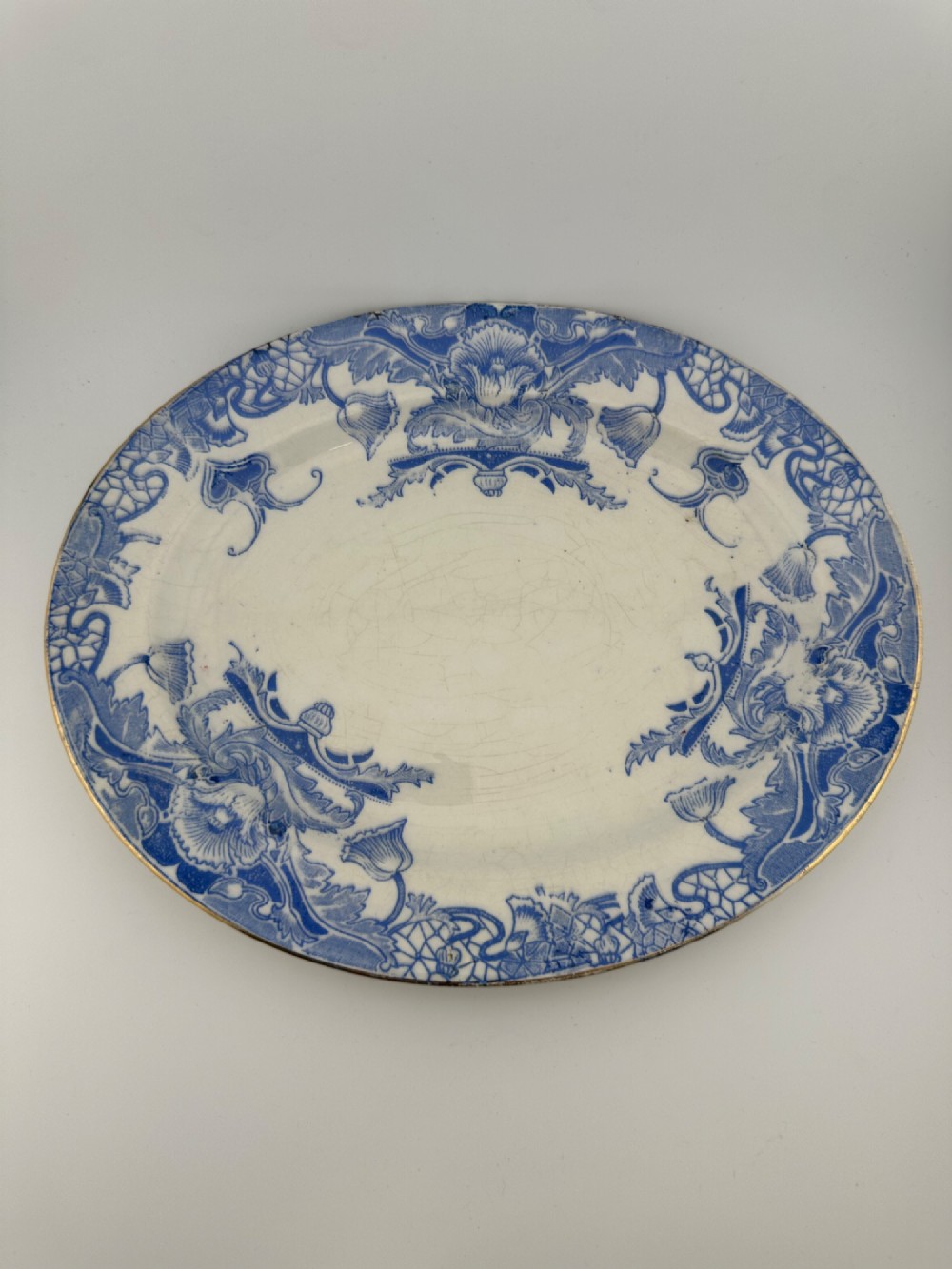 An early Victorian oval earthenware platter featuring a pale blue floral transferware border pattern and a gilded outer rim. View III