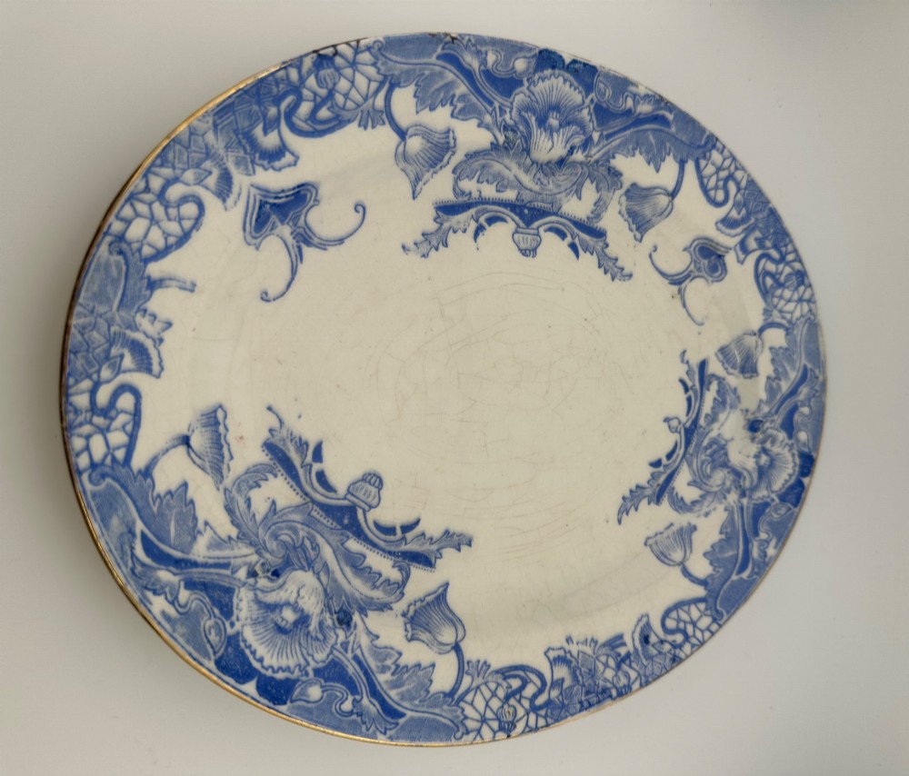 An early Victorian oval earthenware platter featuring a pale blue floral transferware border pattern and a gilded outer rim. View IV