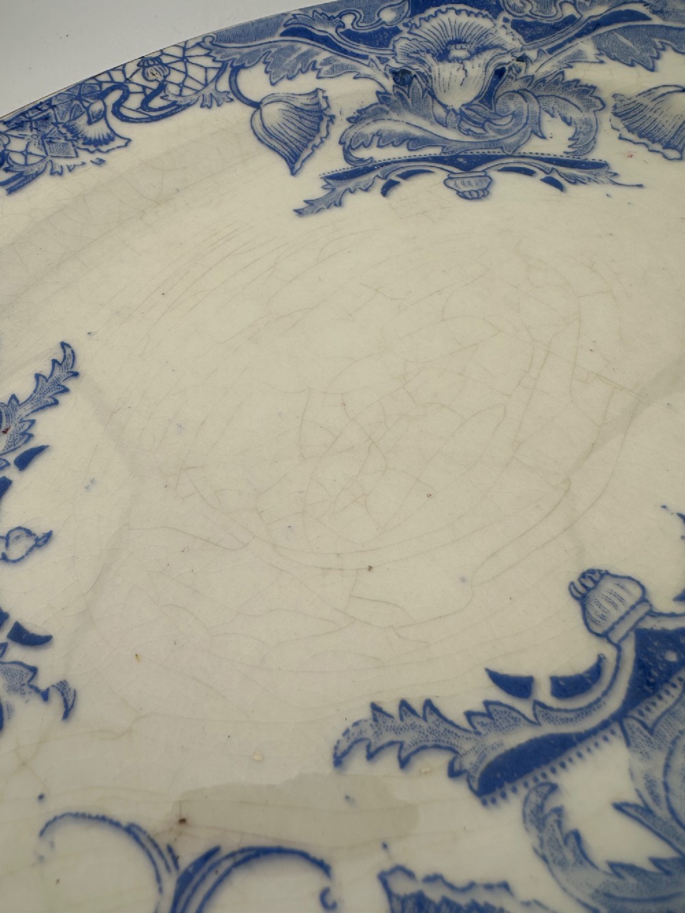 An early Victorian oval earthenware platter featuring a pale blue floral transferware border pattern and a gilded outer rim. View X