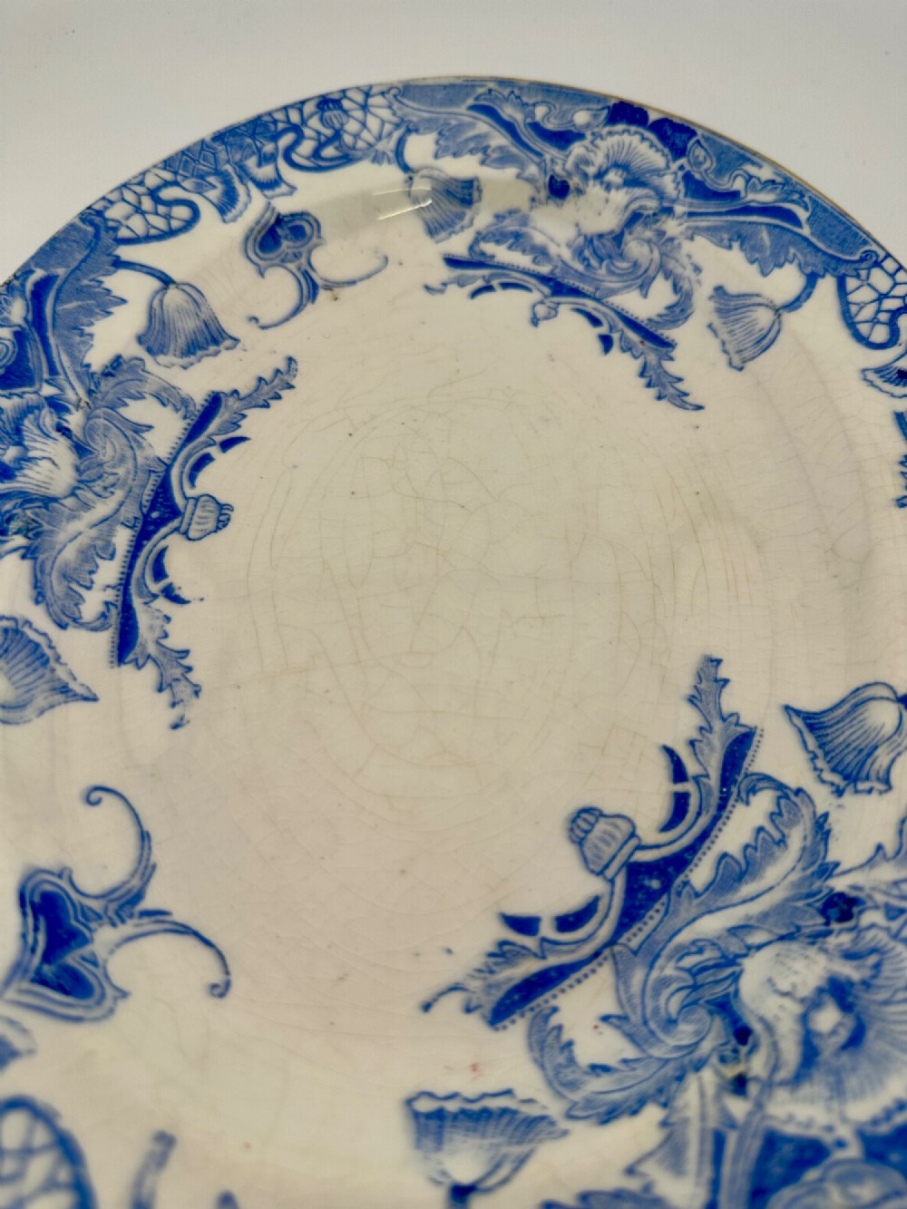 An early Victorian oval earthenware platter featuring a pale blue floral transferware border pattern and a gilded outer rim. View XIII