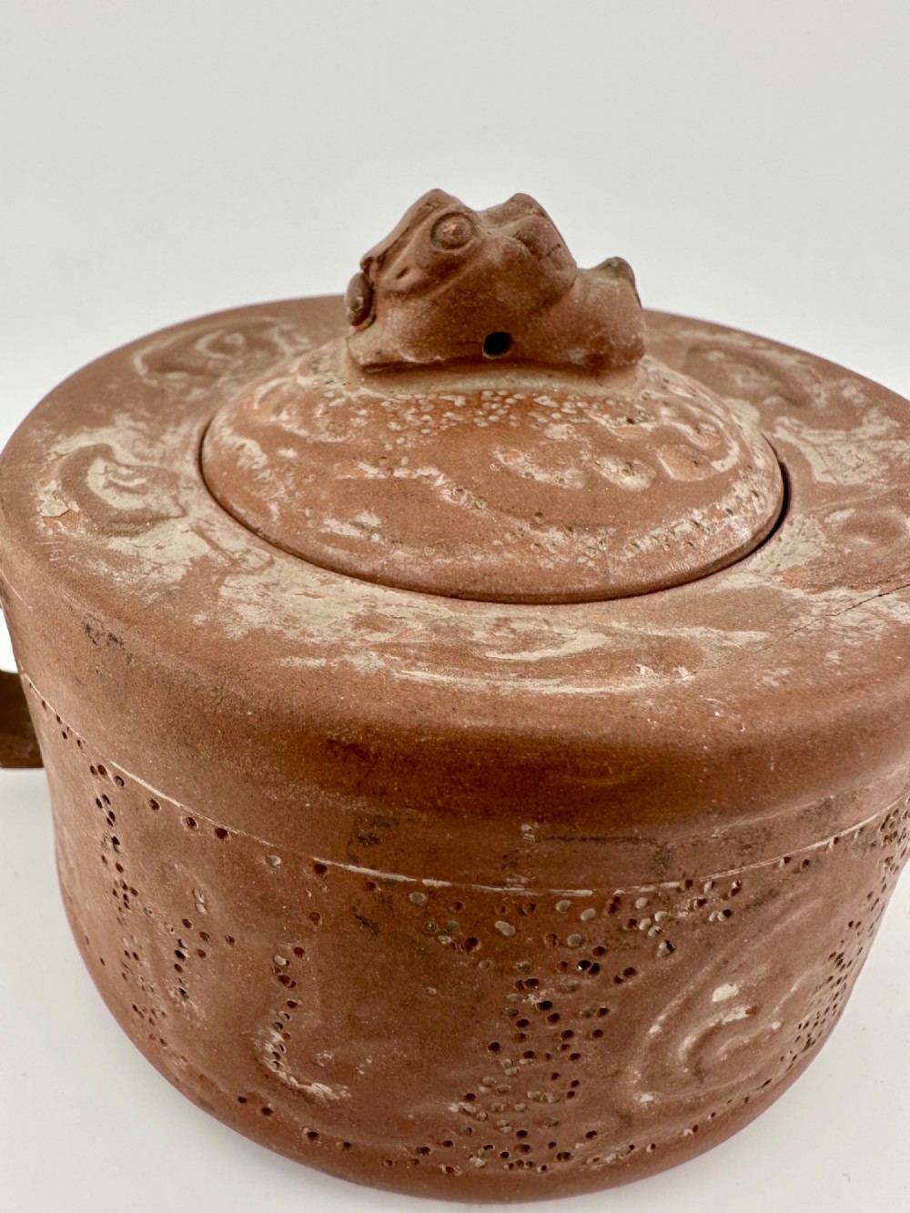 An antique brown Zisha clay teapot featuring archaistic relief decoration and a toad finial on the lid. View II