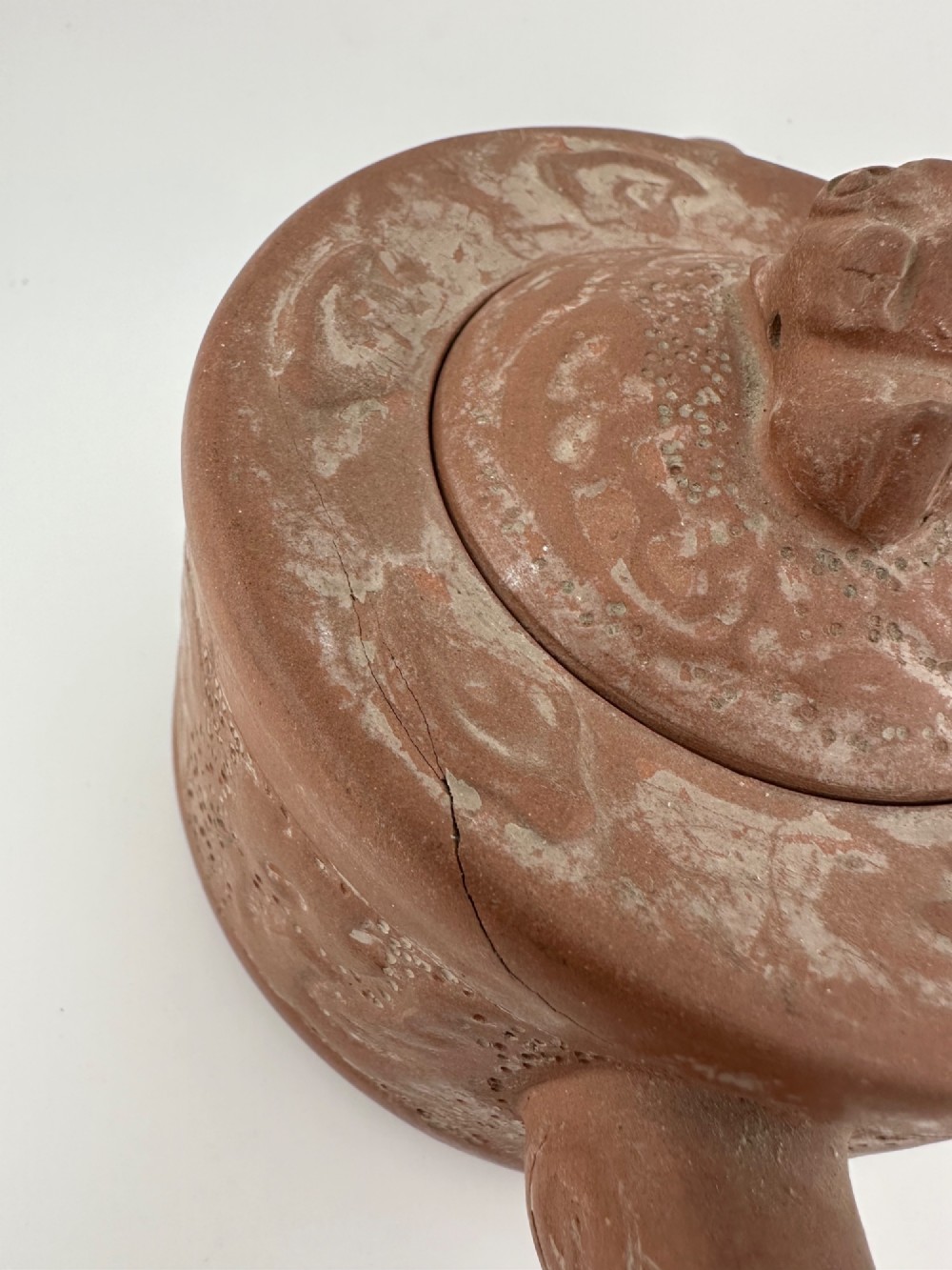 An antique brown Zisha clay teapot featuring archaistic relief decoration and a toad finial on the lid. View V
