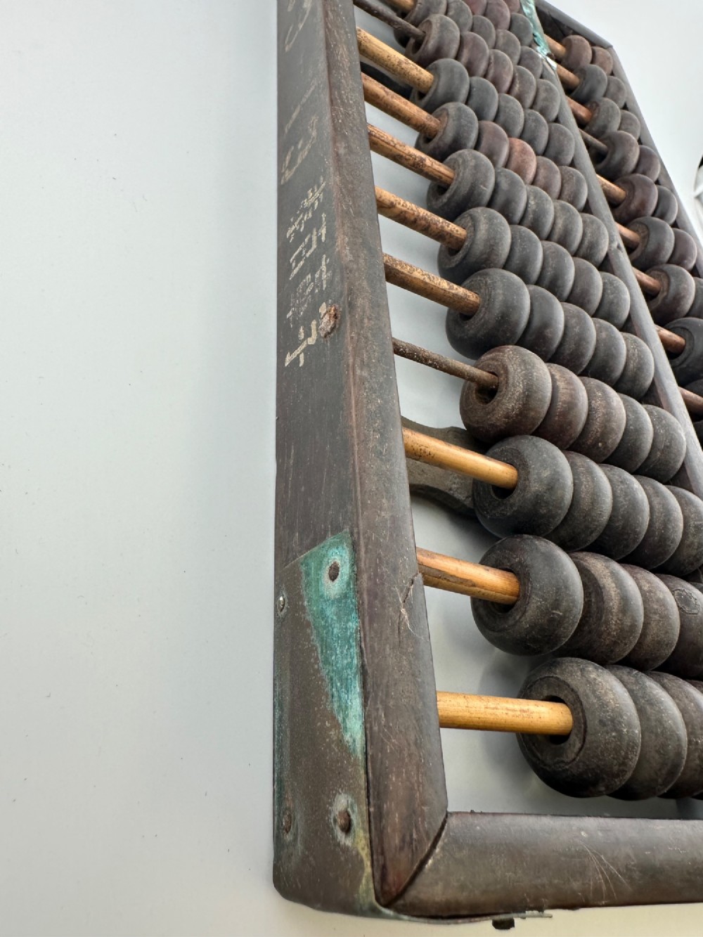 A rectangular dark hardwood Chinese suanpan abacus with two upper beads and five lower beads per rod, reinforced with oxidised brass plates. View II