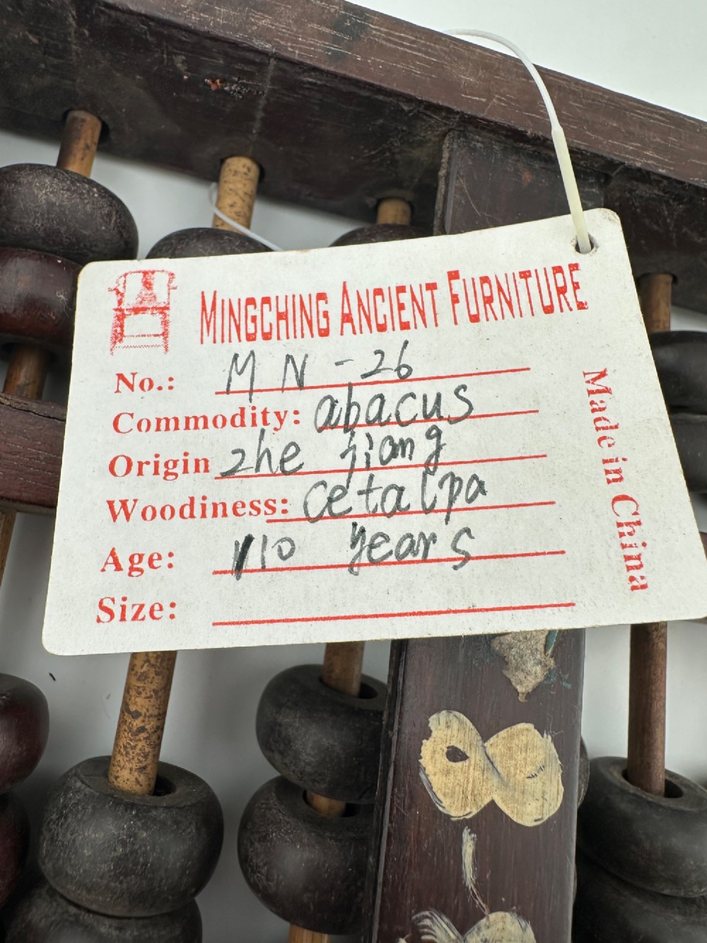 A rectangular dark hardwood Chinese suanpan abacus with two upper beads and five lower beads per rod, reinforced with oxidised brass plates. View VI