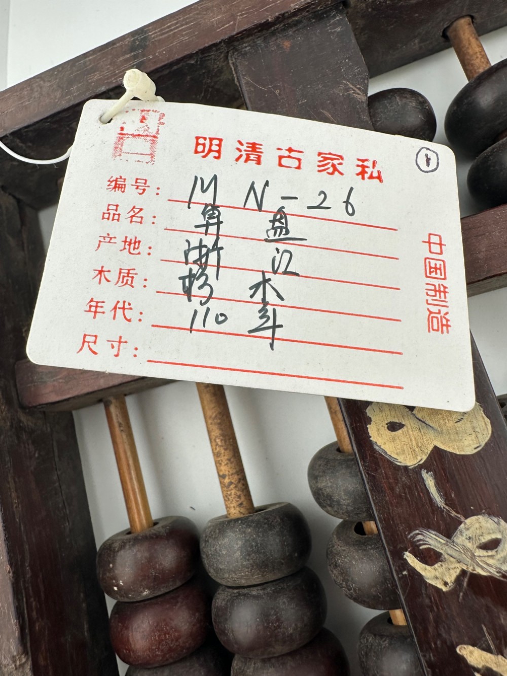A rectangular dark hardwood Chinese suanpan abacus with two upper beads and five lower beads per rod, reinforced with oxidised brass plates. View VII