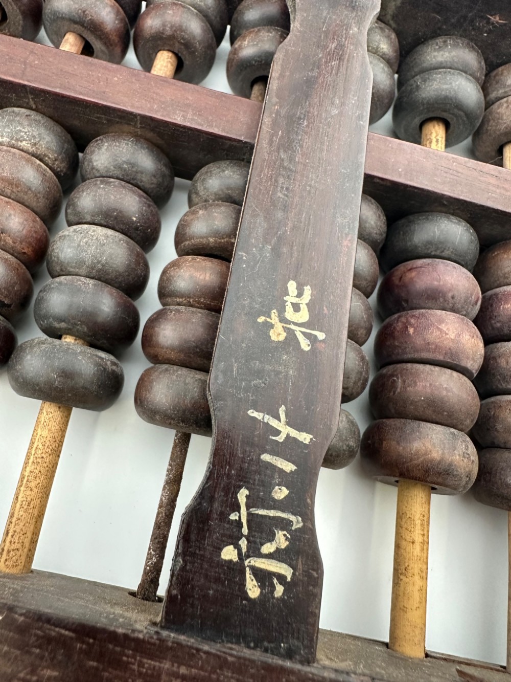 A rectangular dark hardwood Chinese suanpan abacus with two upper beads and five lower beads per rod, reinforced with oxidised brass plates. View VIII