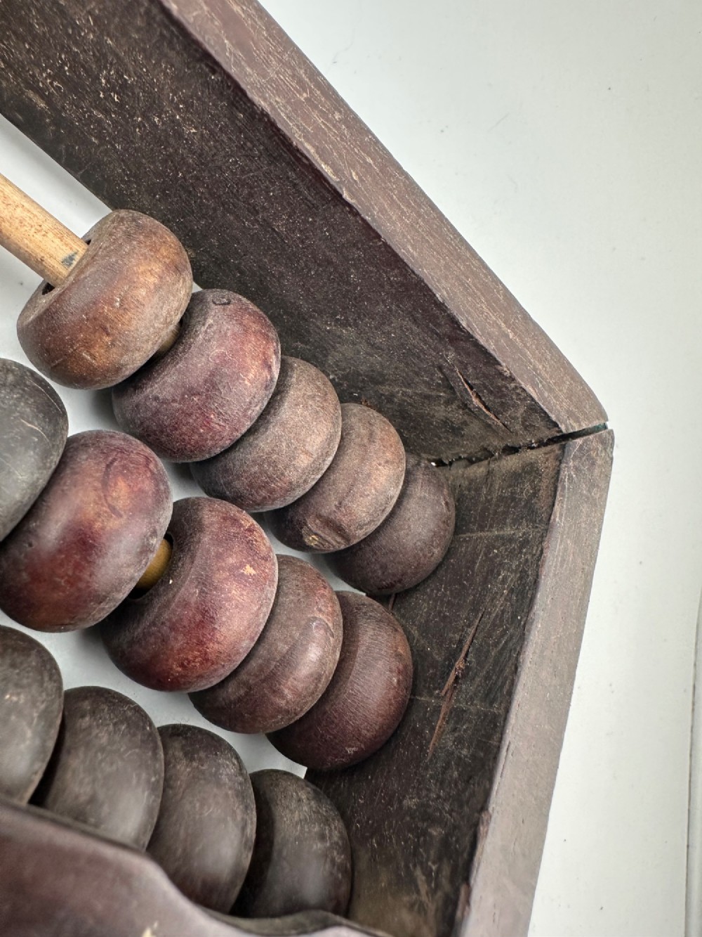 A rectangular dark hardwood Chinese suanpan abacus with two upper beads and five lower beads per rod, reinforced with oxidised brass plates. View IX