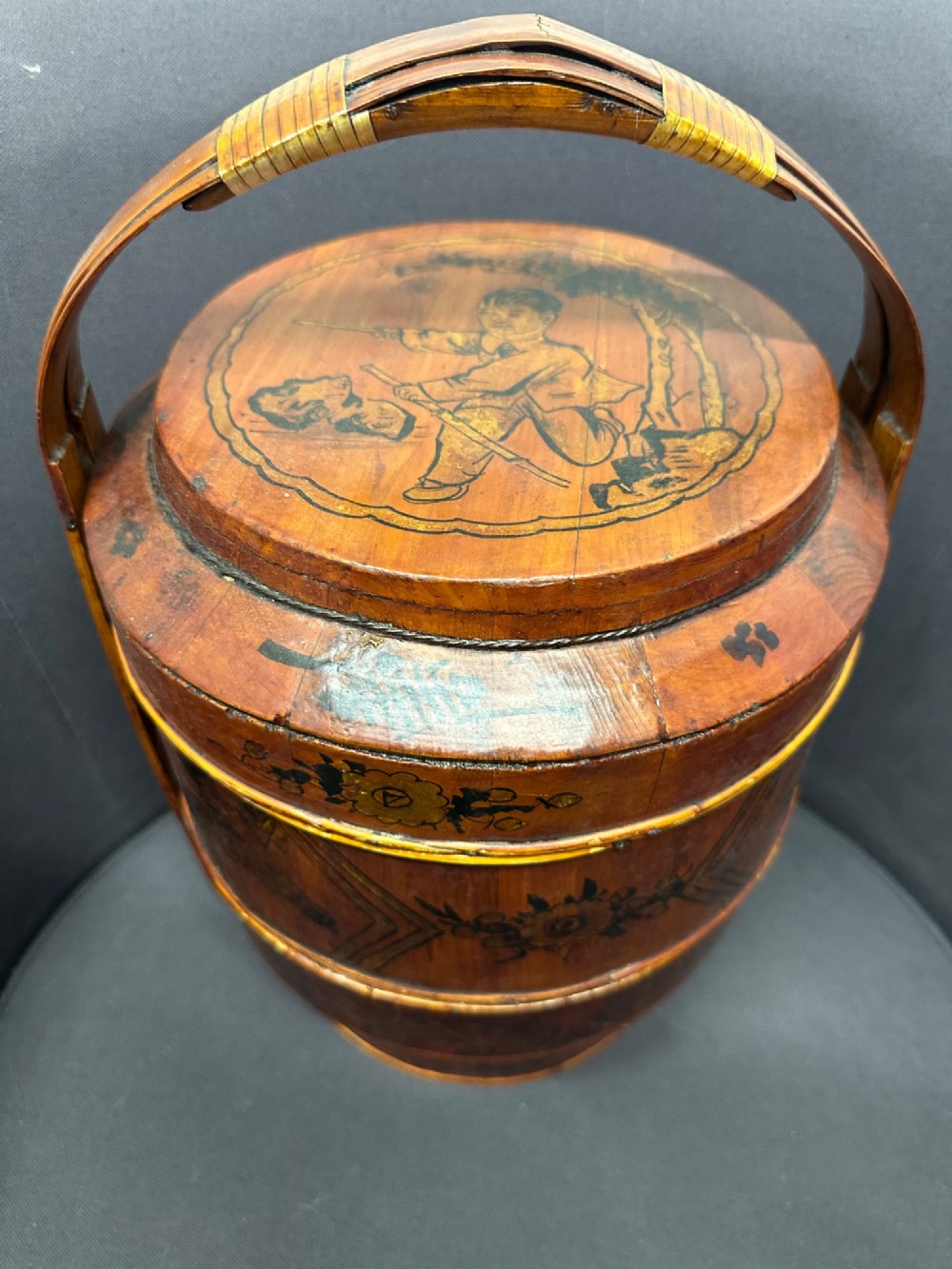 A three-tiered late 19th-century Chinese bamboo and wood food carrier with an arched handle, featuring hand-painted yellow flowers, birds, and goldfish against a warm brown lacquer finish. View II