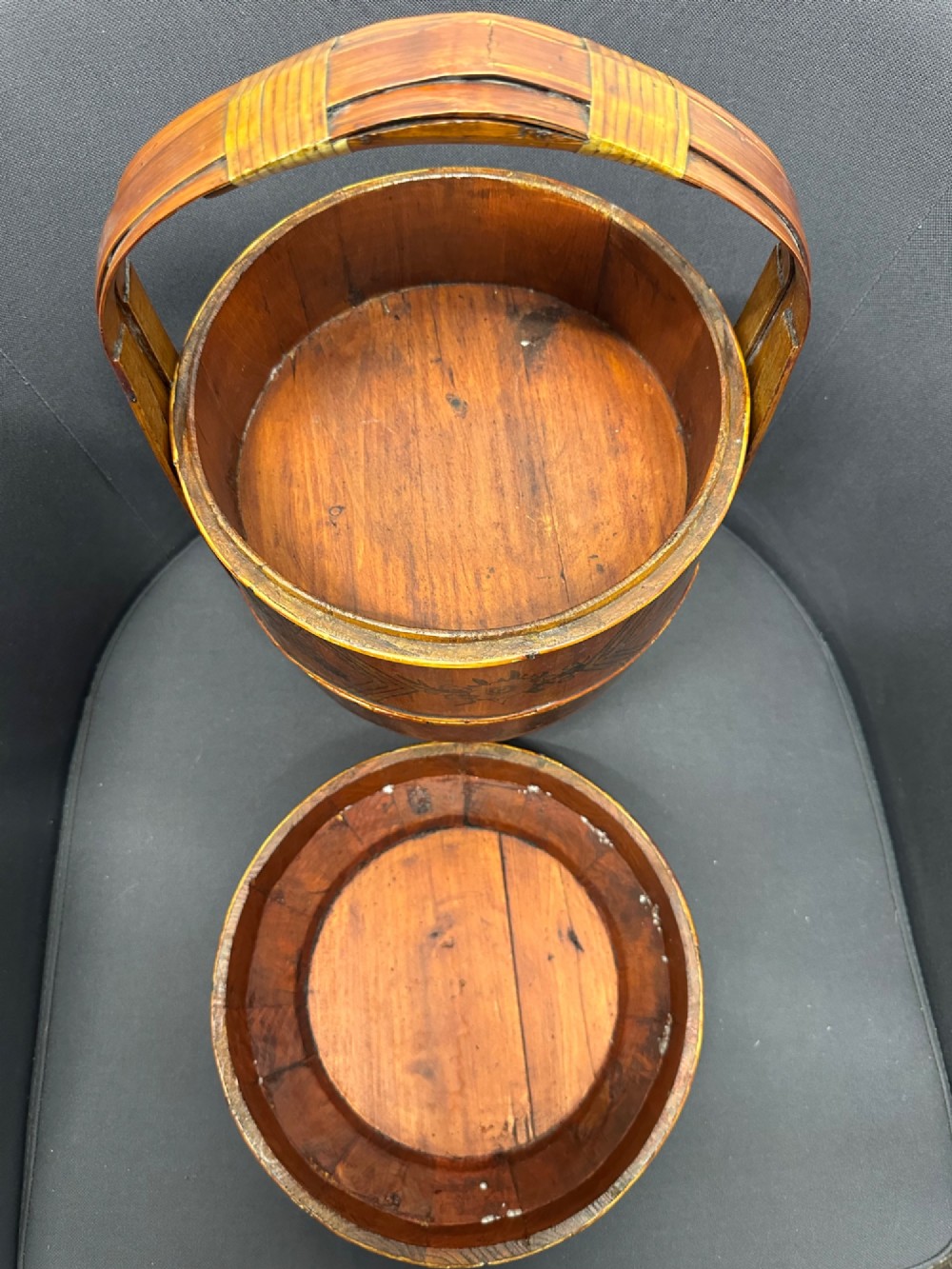 A three-tiered late 19th-century Chinese bamboo and wood food carrier with an arched handle, featuring hand-painted yellow flowers, birds, and goldfish against a warm brown lacquer finish. View VIII