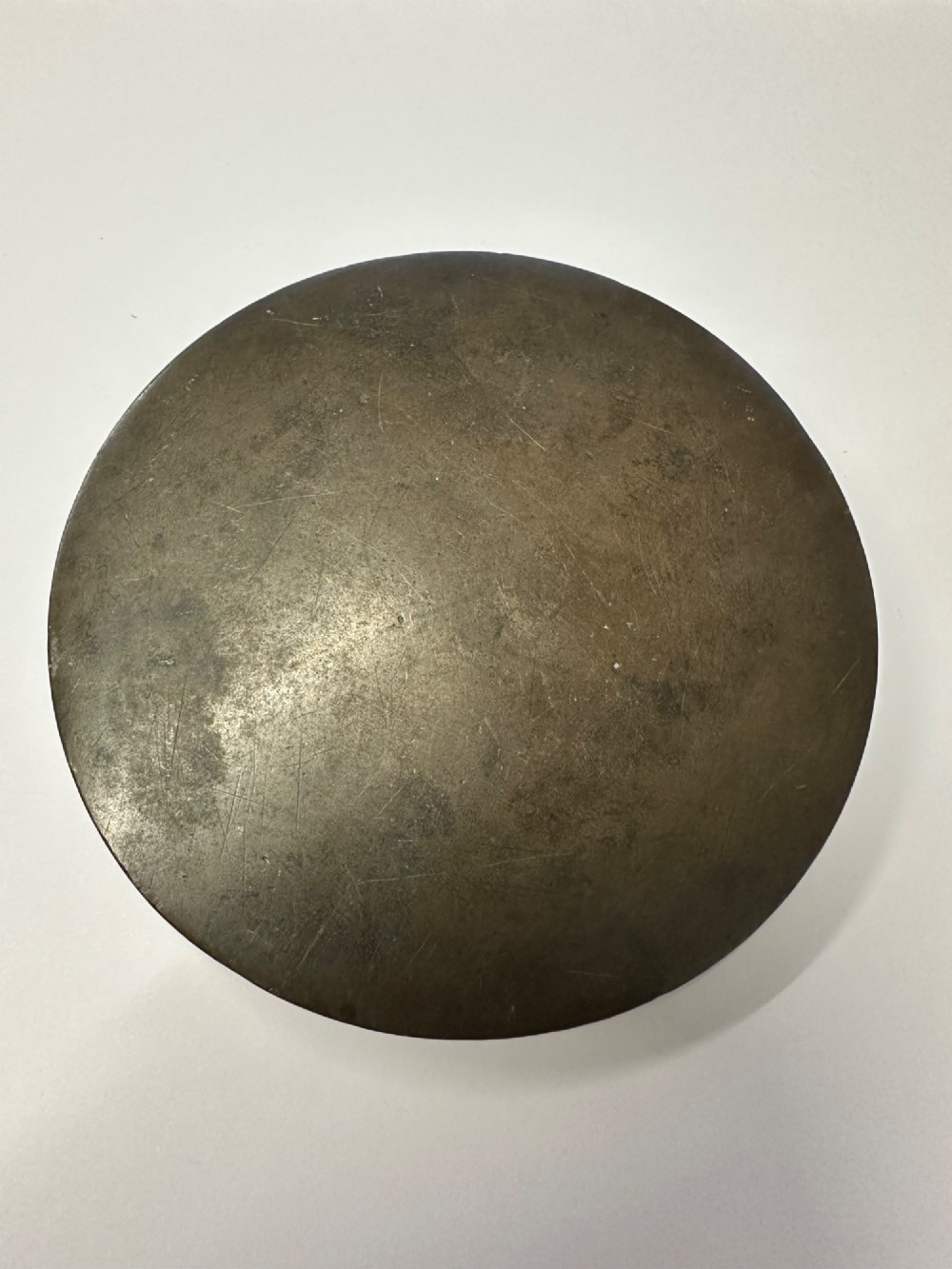 A circular ancient bronze mirror back featuring a prominent central knob, raised concentric circular borders, and stylized dragon motifs in low relief. View III