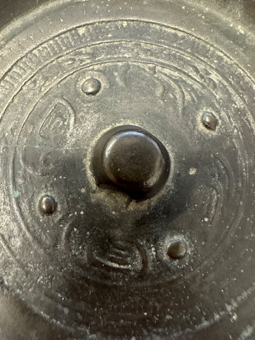 A circular ancient bronze mirror back featuring a prominent central knob, raised concentric circular borders, and stylized dragon motifs in low relief. View IV