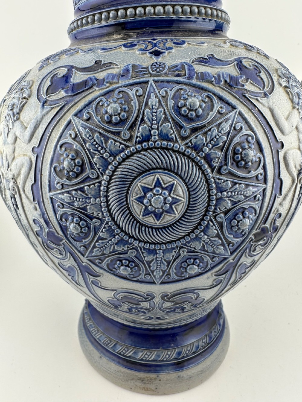 A blue and grey salt-glazed stoneware jug featuring relief-moulded geometric patterns, mask motifs, and a hinged pewter lid. View VIII