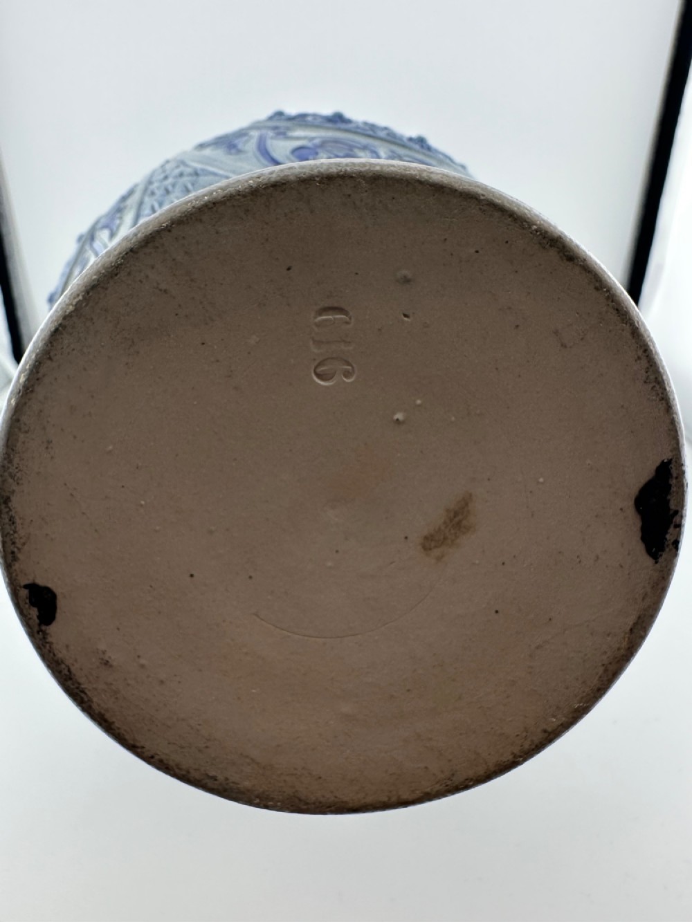 A blue and grey salt-glazed stoneware jug featuring relief-moulded geometric patterns, mask motifs, and a hinged pewter lid. View XII