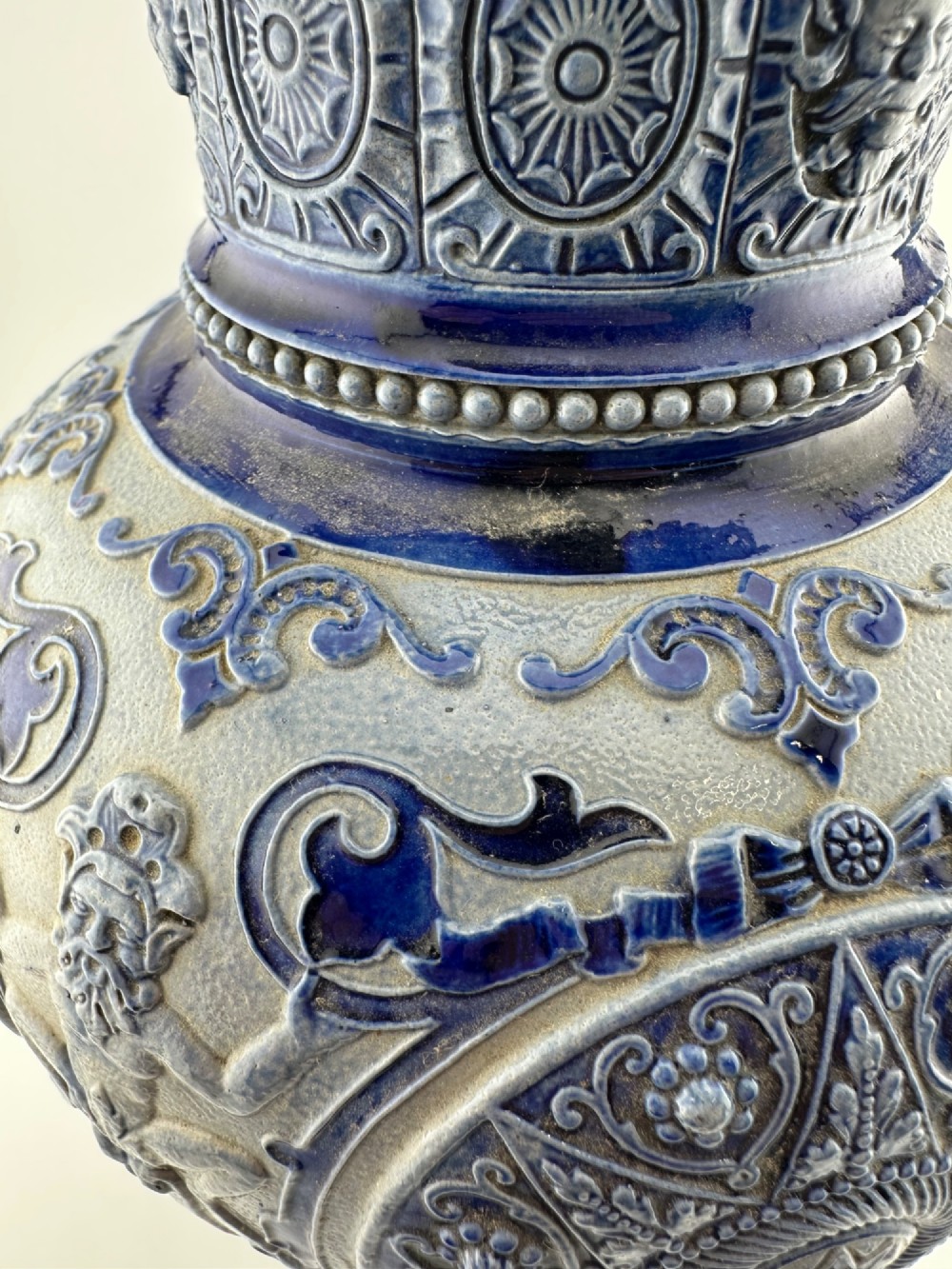 A blue and grey salt-glazed stoneware jug featuring relief-moulded geometric patterns, mask motifs, and a hinged pewter lid. View XV