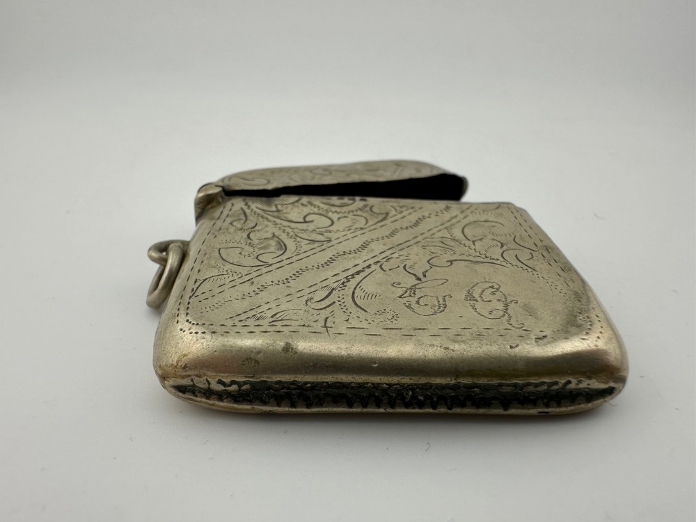 An antique rectangular silver-plated vesta case featuring hand-engraved scrollwork, an open hinged lid, and a side suspension ring. View II