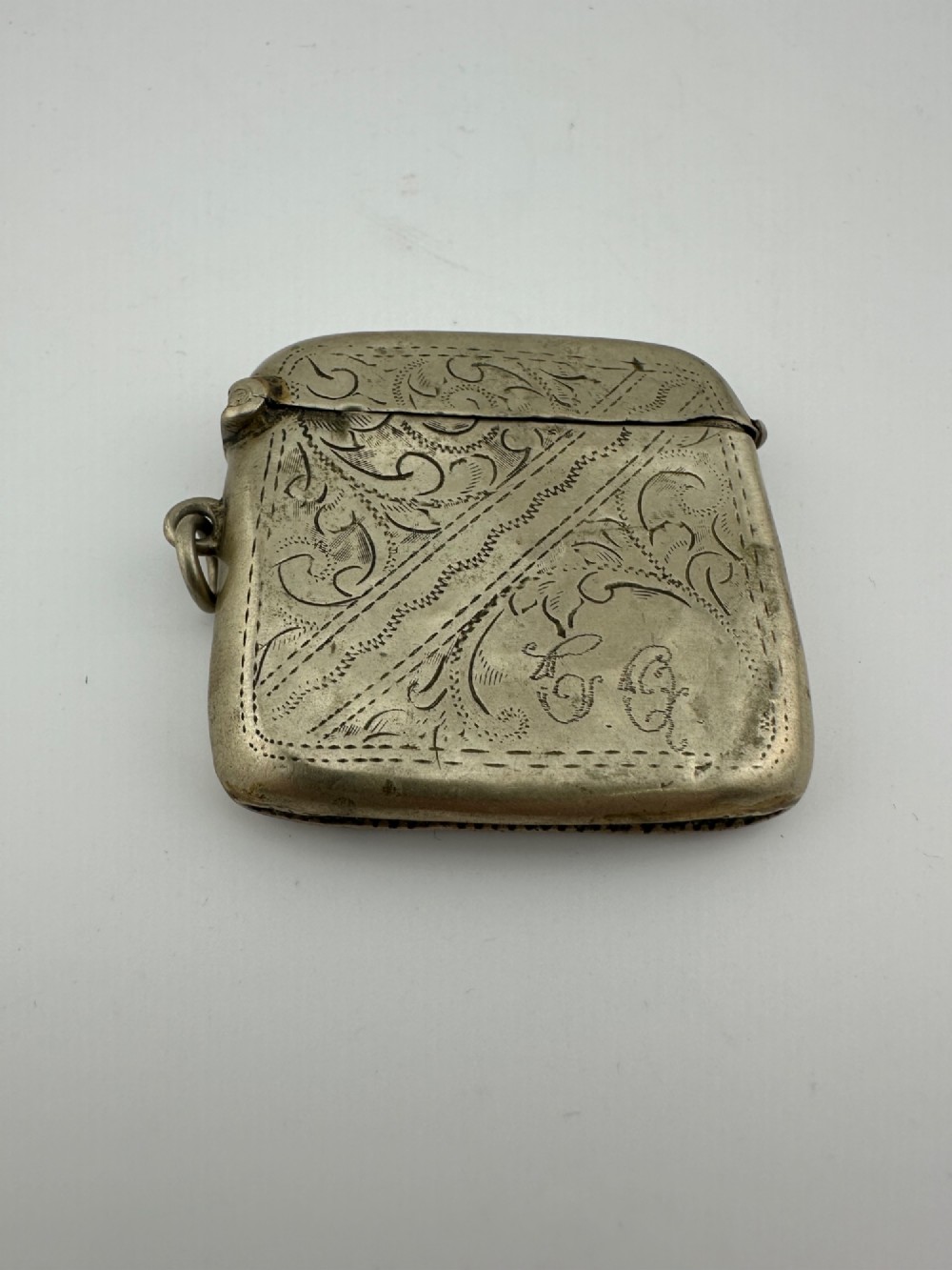An antique rectangular silver-plated vesta case featuring hand-engraved scrollwork, an open hinged lid, and a side suspension ring. View III