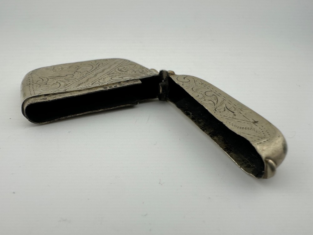 An antique rectangular silver-plated vesta case featuring hand-engraved scrollwork, an open hinged lid, and a side suspension ring. View VI