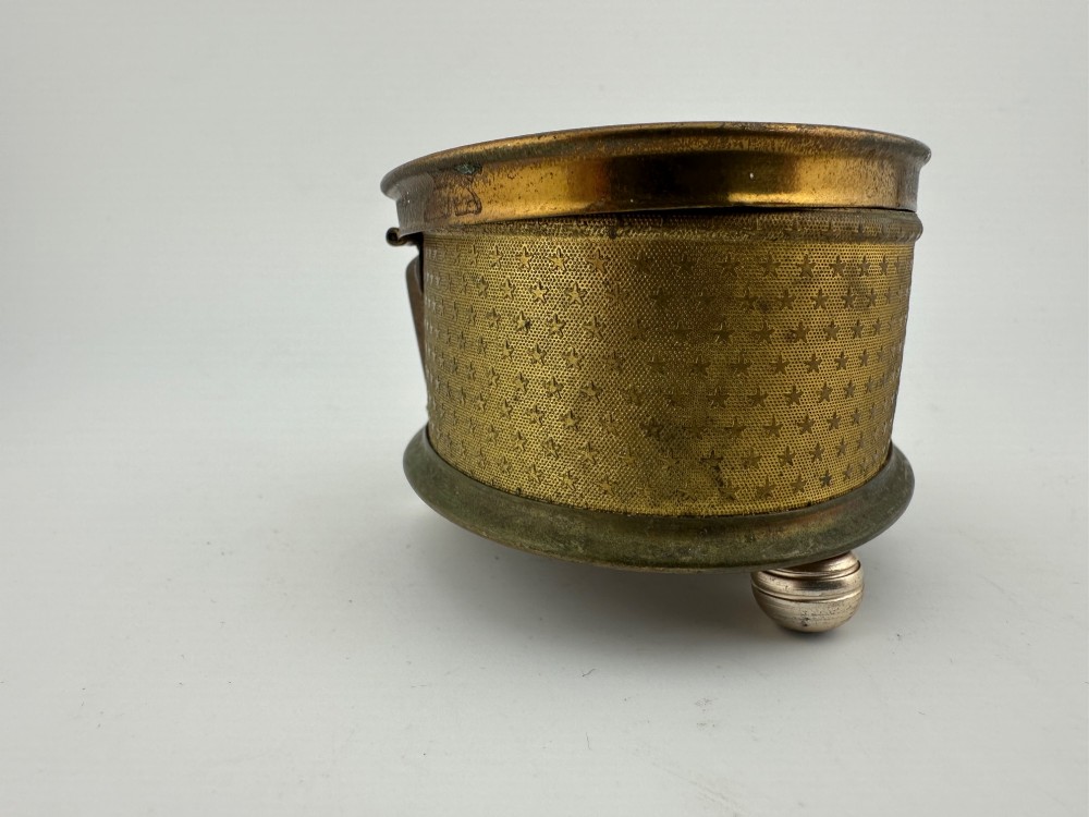 An oval vintage metal trinket box featuring a printed floral motif on the lid, star-patterned side panels, small rounded feet, and a velvet lining. View VIII