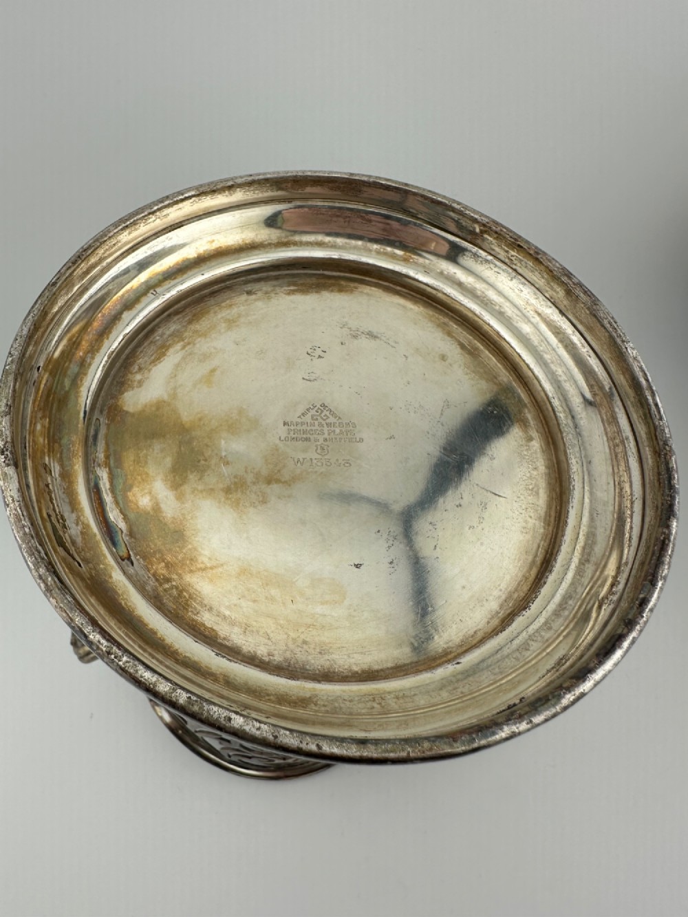 An antique silver-plated cylindrical wine bottle holder featuring pierced scroll fretwork, two side handles, and a flared circular base. View VIII