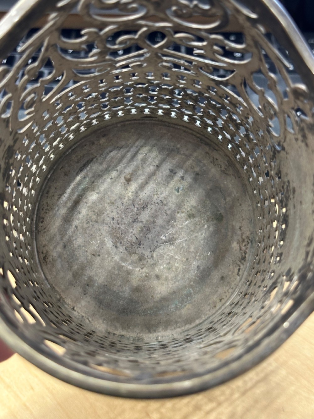 An antique silver-plated cylindrical wine bottle holder featuring pierced scroll fretwork, two side handles, and a flared circular base. View IX
