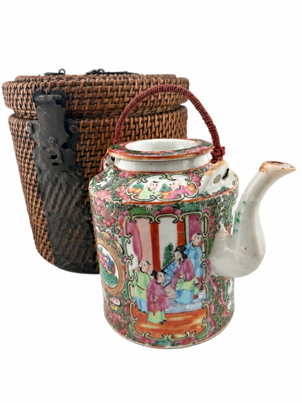 A Chinese Famille Rose cylindrical ceramic teapot with hand-painted court figures set beside its fitted woven wicker carrying case.