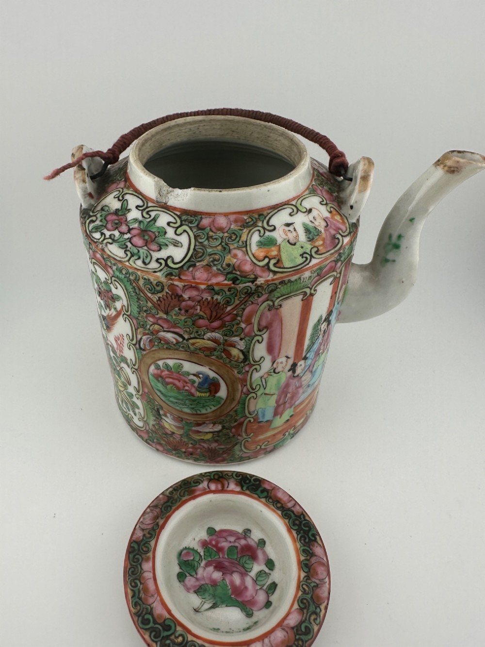 A Chinese Famille Rose cylindrical ceramic teapot with hand-painted court figures set beside its fitted woven wicker carrying case. View IX
