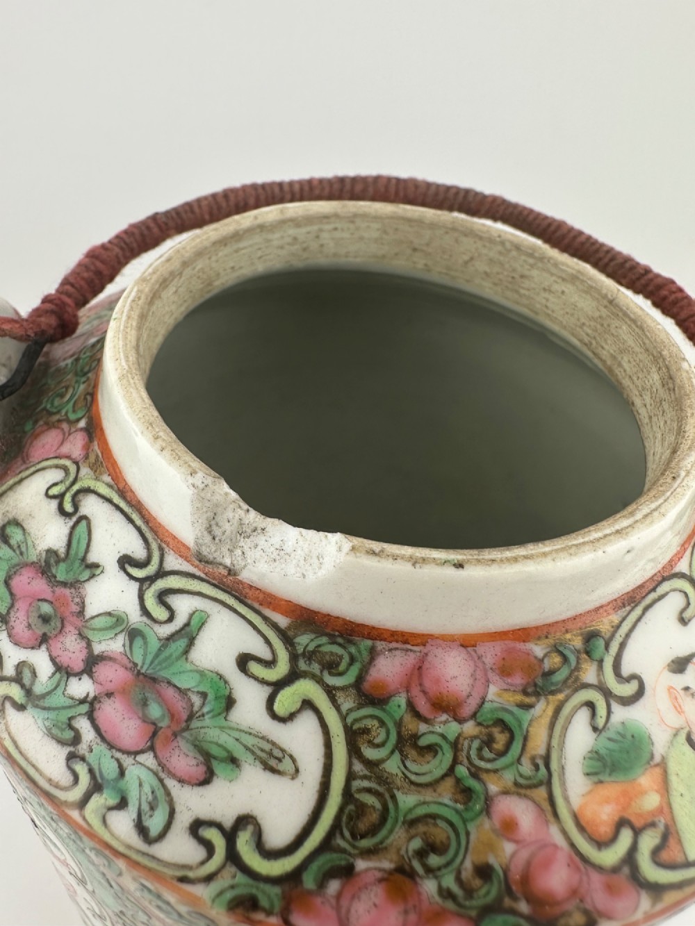 A Chinese Famille Rose cylindrical ceramic teapot with hand-painted court figures set beside its fitted woven wicker carrying case. View XI