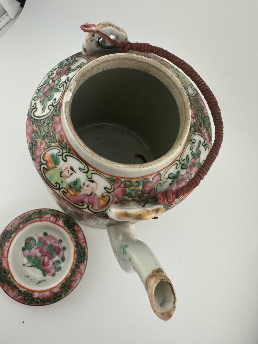 A Chinese Famille Rose cylindrical ceramic teapot with hand-painted court figures set beside its fitted woven wicker carrying case. View XII