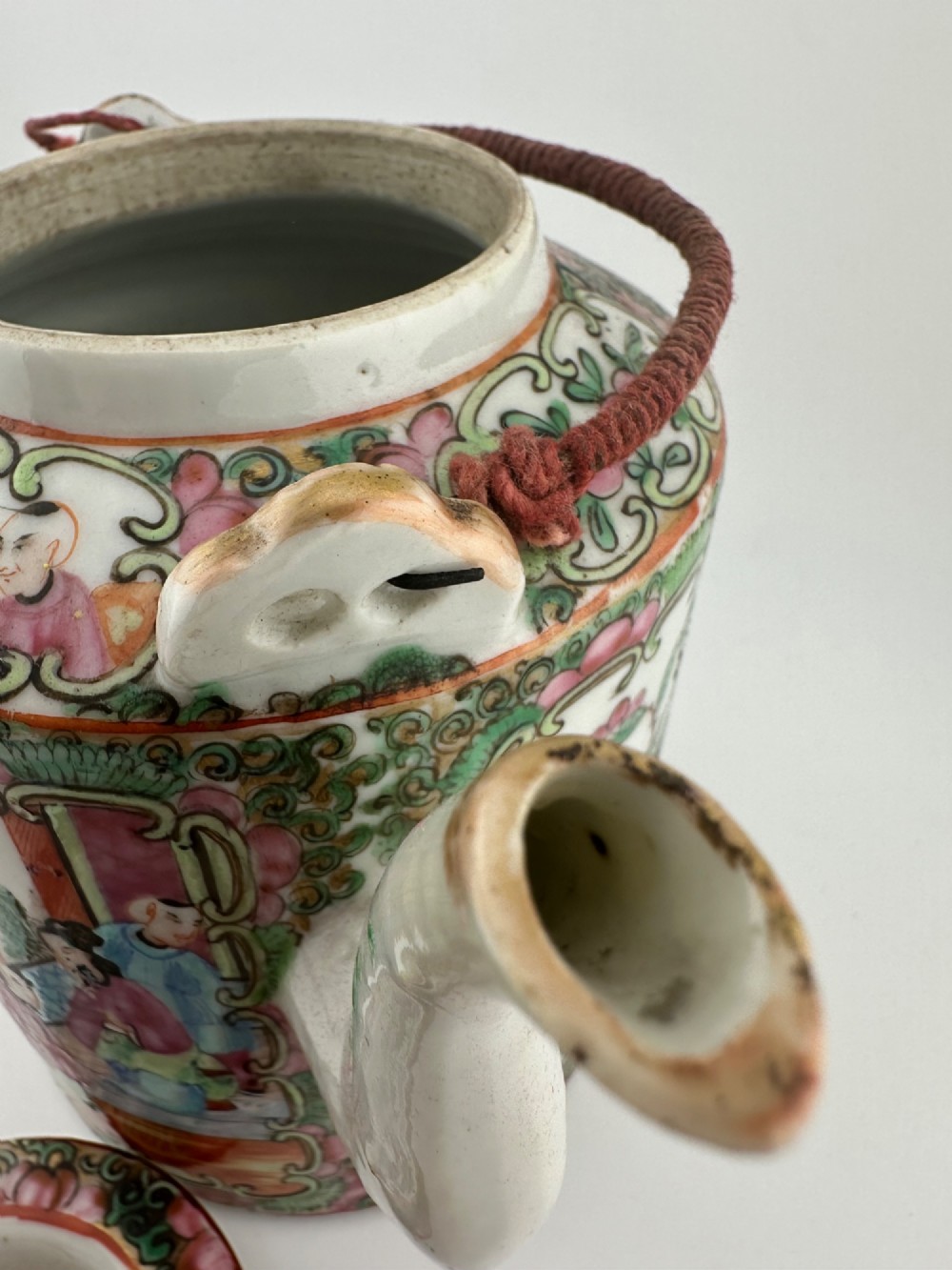 A Chinese Famille Rose cylindrical ceramic teapot with hand-painted court figures set beside its fitted woven wicker carrying case. View XIII