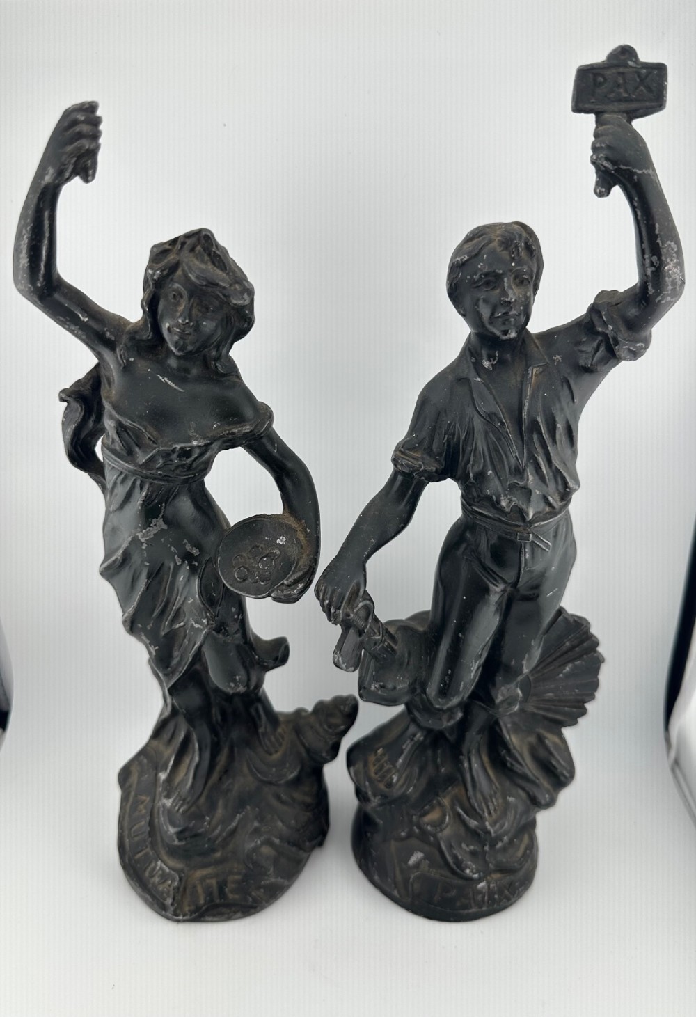 A pair of dark bronze-finished French spelter allegorical figures raised on moulded circular bases representing Mutualite and Paix.
