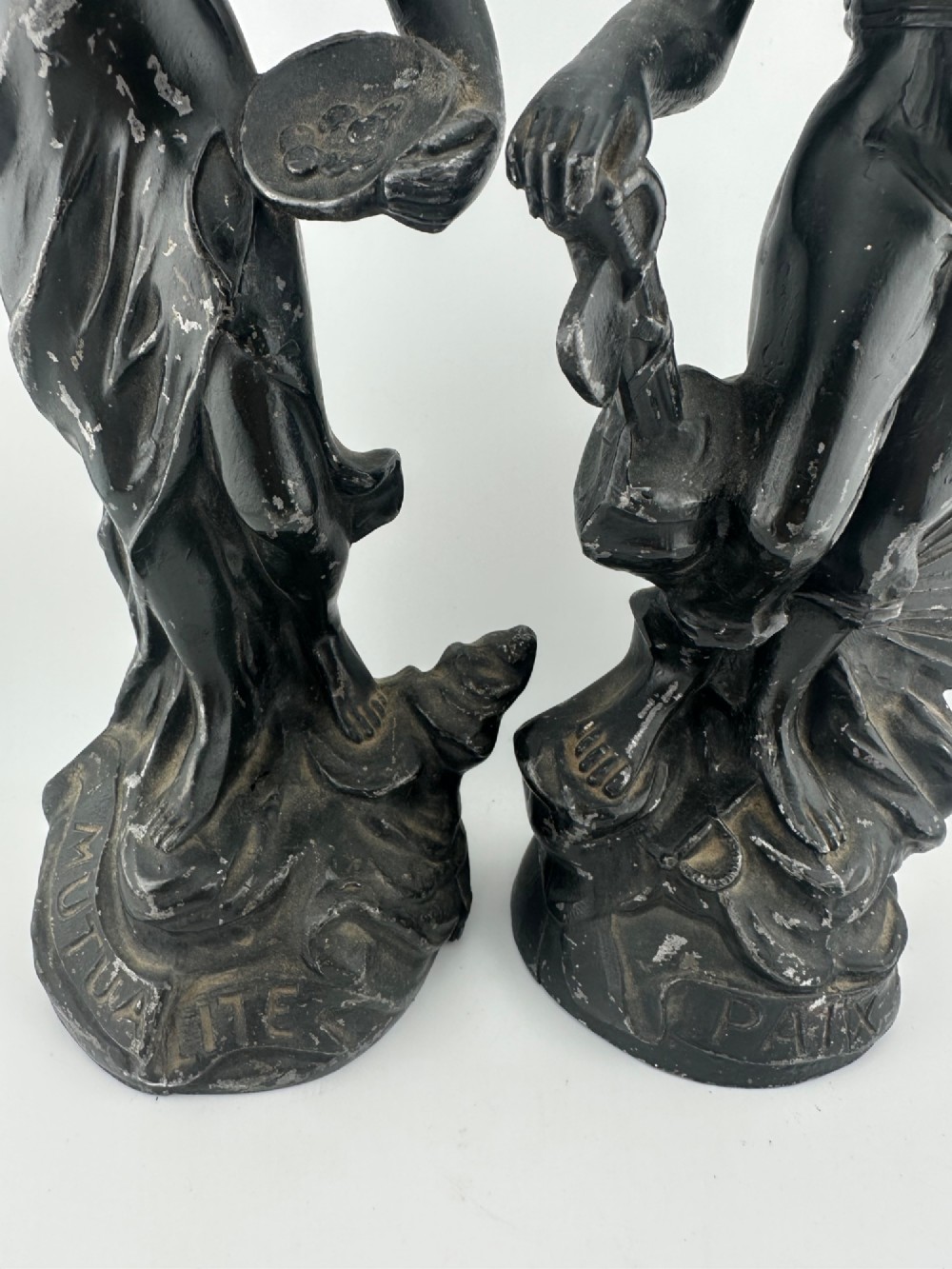 A pair of dark bronze-finished French spelter allegorical figures raised on moulded circular bases representing Mutualite and Paix. View II