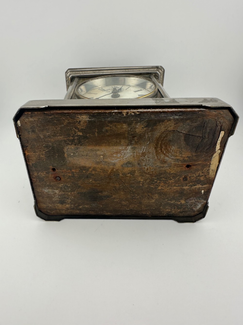 An Edwardian carriage clock with a silvered metal casing, brass carrying handle, and engraved brass mask around a white enamel dial. View XI