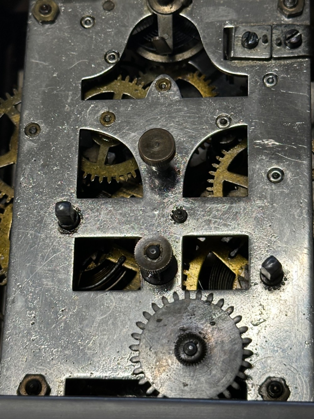 An Edwardian carriage clock with a silvered metal casing, brass carrying handle, and engraved brass mask around a white enamel dial. View XII