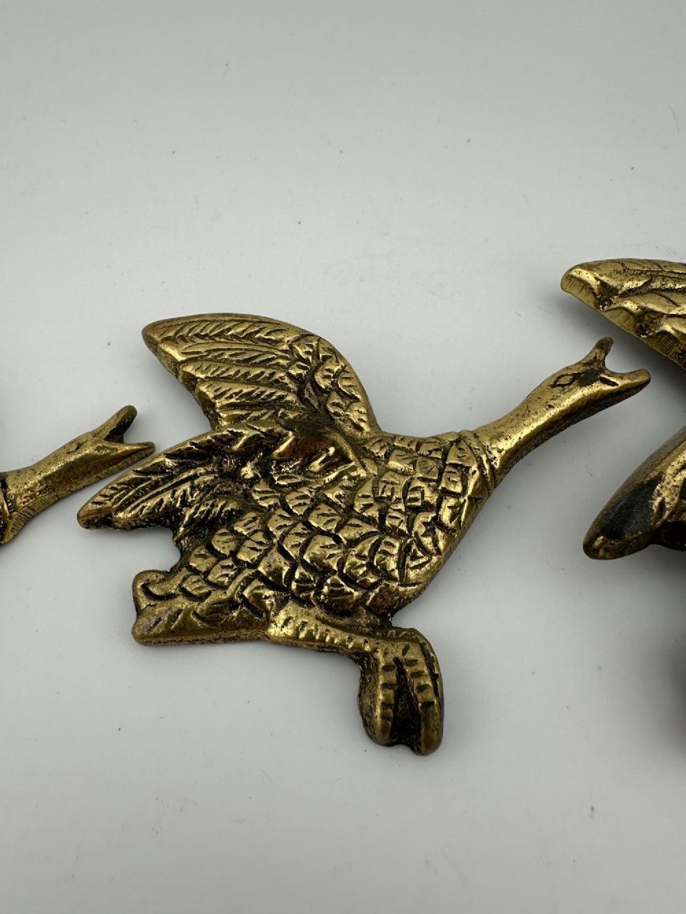 A set of three graduated cast brass flying geese wall plaques arranged by size with textured feather detailing. View IV