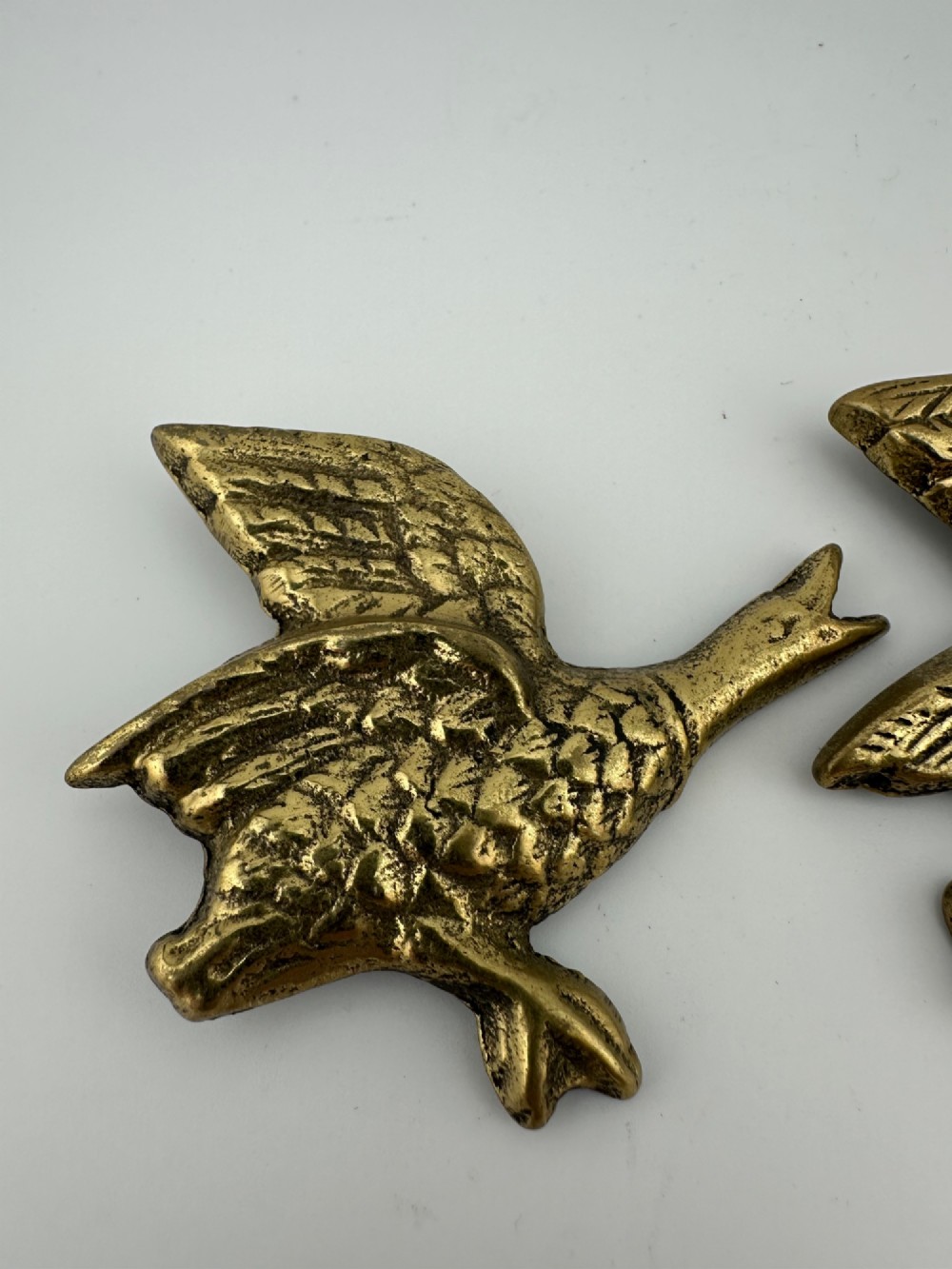 A set of three graduated cast brass flying geese wall plaques arranged by size with textured feather detailing. View V