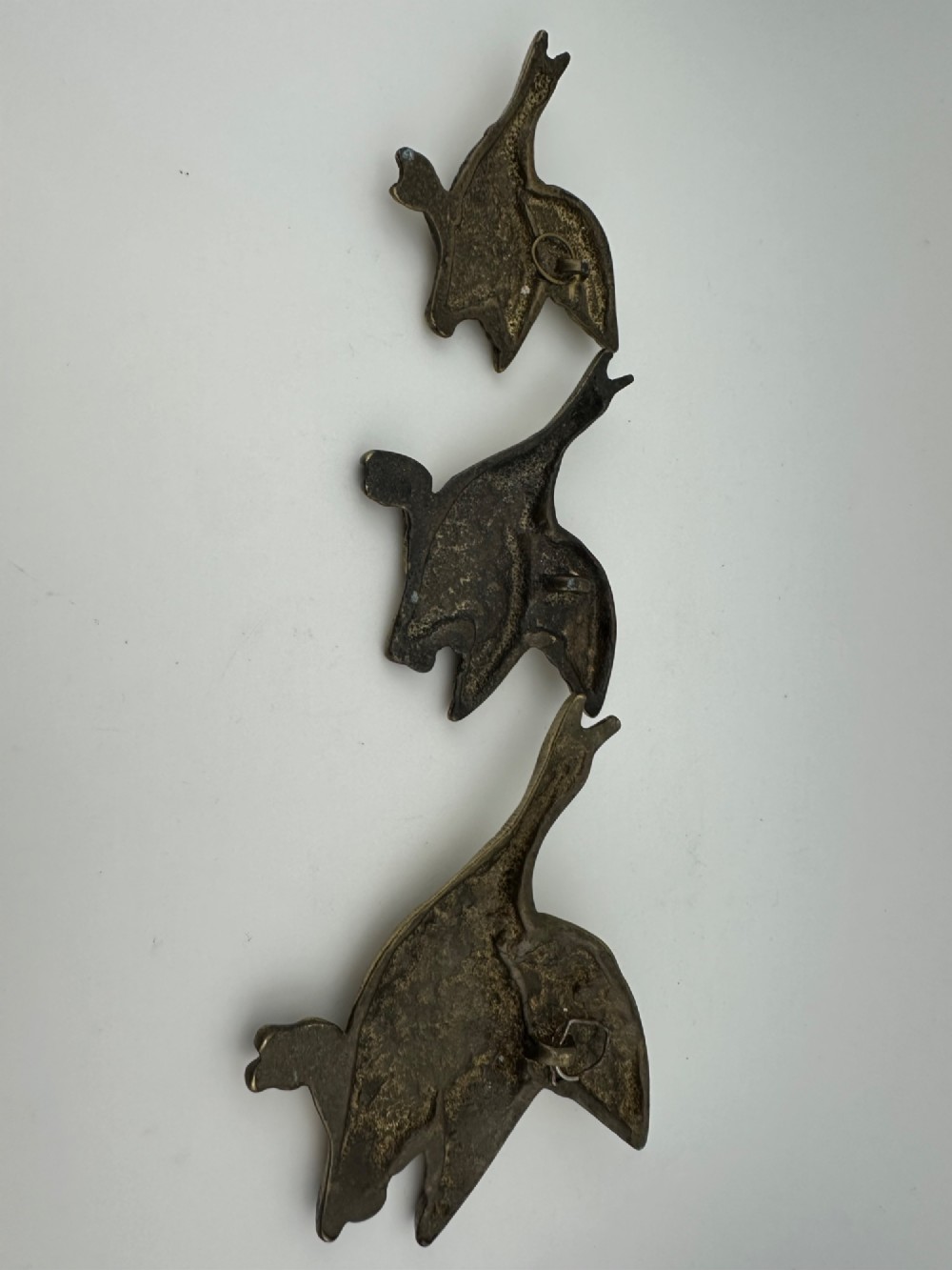 A set of three graduated cast brass flying geese wall plaques arranged by size with textured feather detailing. View VI