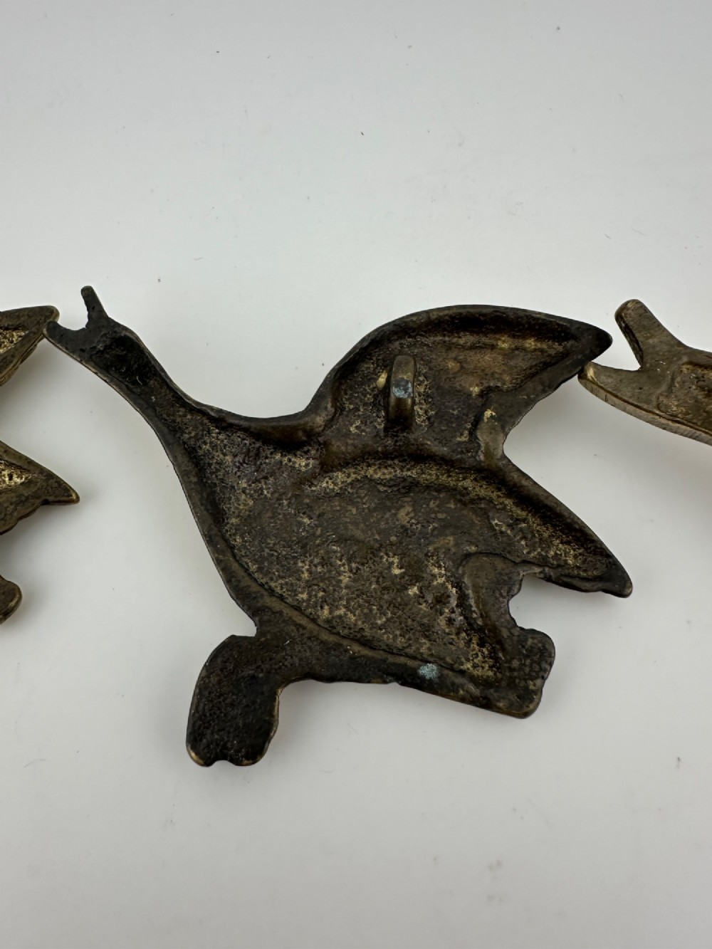 A set of three graduated cast brass flying geese wall plaques arranged by size with textured feather detailing. View VIII