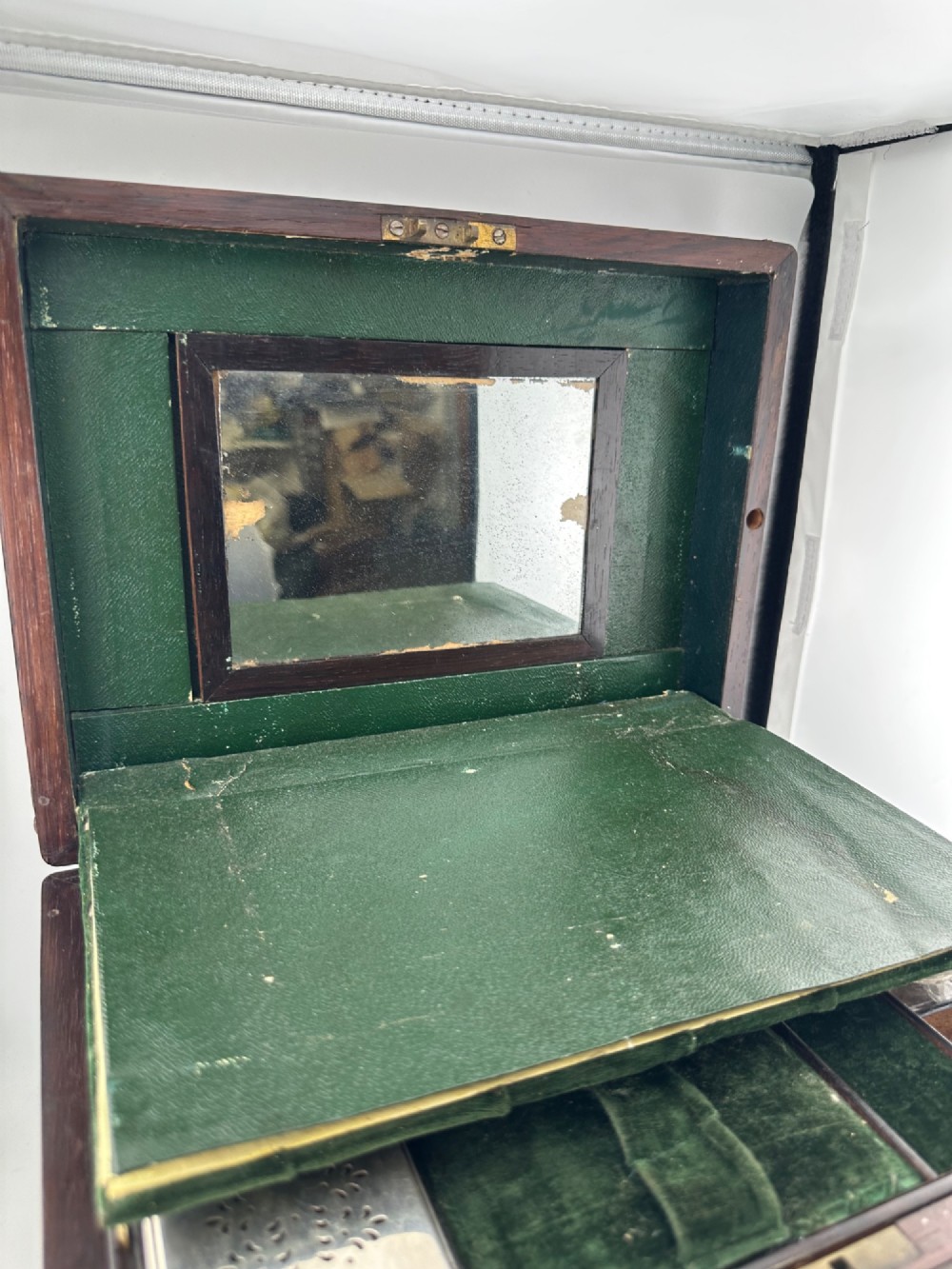An open Victorian rosewood vanity box featuring a ruched green velvet lid lining, fitted interior compartments with silver-capped glass bottles, and a mother-of-pearl escutcheon. View X