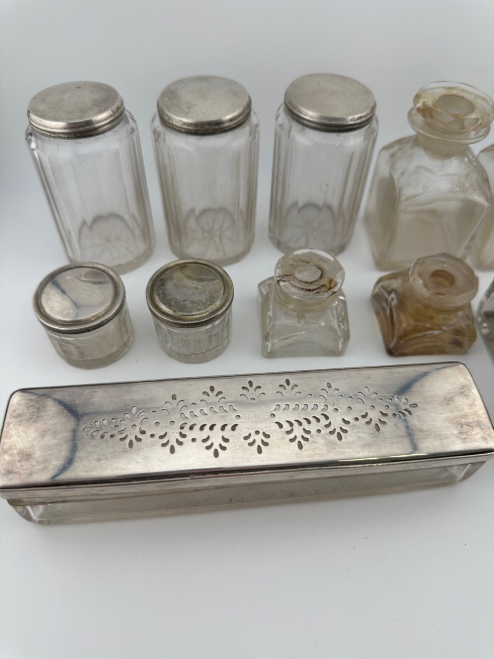 An open Victorian rosewood vanity box featuring a ruched green velvet lid lining, fitted interior compartments with silver-capped glass bottles, and a mother-of-pearl escutcheon. View XV