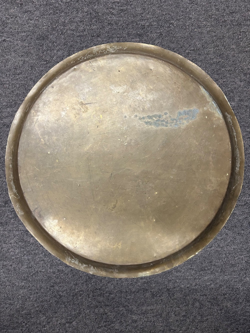 A large circular brass tray featuring intricate hand-engraved concentric floral and geometric patterns with a shallow rolled rim. View IV