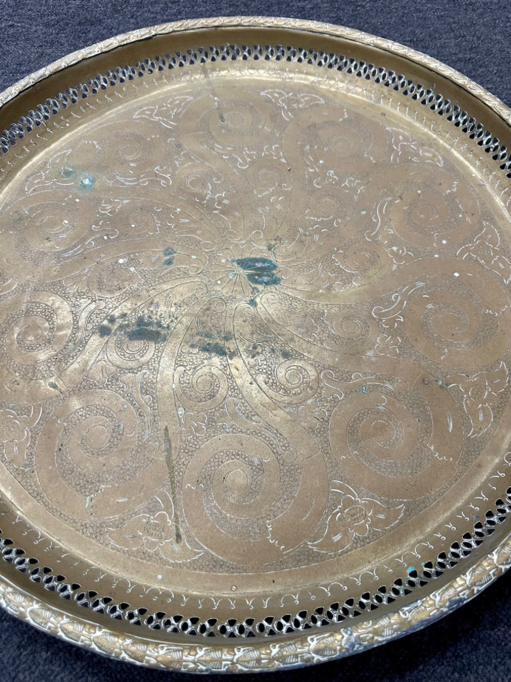 A circular antique brass tray featuring an intricately engraved swirling floral pattern and a pierced gallery rim. View II