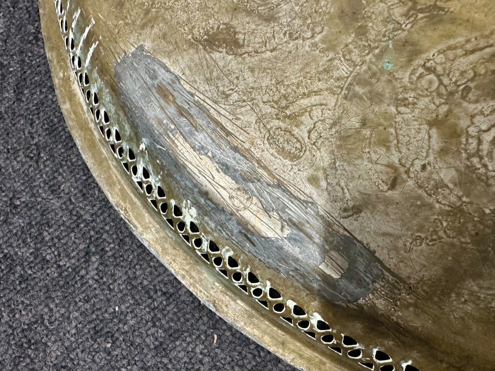 A circular antique brass tray featuring an intricately engraved swirling floral pattern and a pierced gallery rim. View VI
