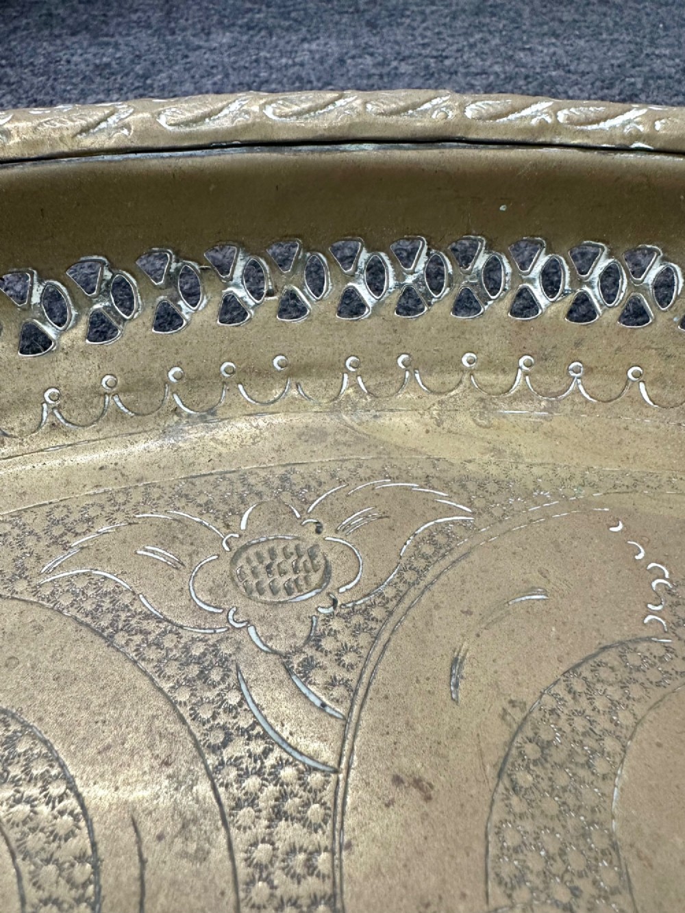 A circular antique brass tray featuring an intricately engraved swirling floral pattern and a pierced gallery rim. View VII