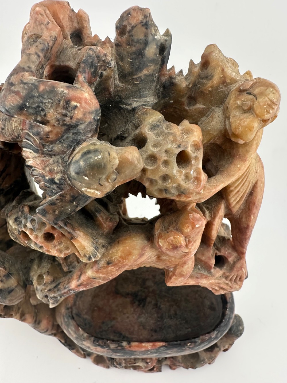 A Qing dynasty Chinese soapstone carving depicting a small vase, a shallow brush washer basin, and carved birds among naturalistic floral motifs in mottled red, grey, and cream stone. View VII