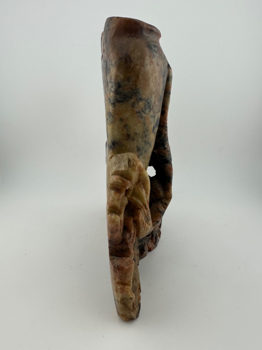 A Qing dynasty Chinese soapstone carving depicting a small vase, a shallow brush washer basin, and carved birds among naturalistic floral motifs in mottled red, grey, and cream stone. View IX