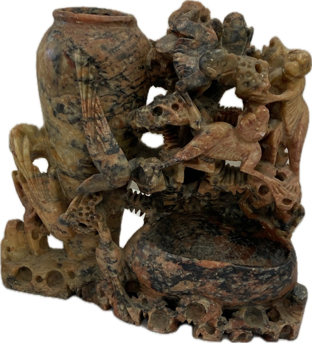A Qing dynasty Chinese soapstone carving depicting a small vase, a shallow brush washer basin, and carved birds among naturalistic floral motifs in mottled red, grey, and cream stone. View XI