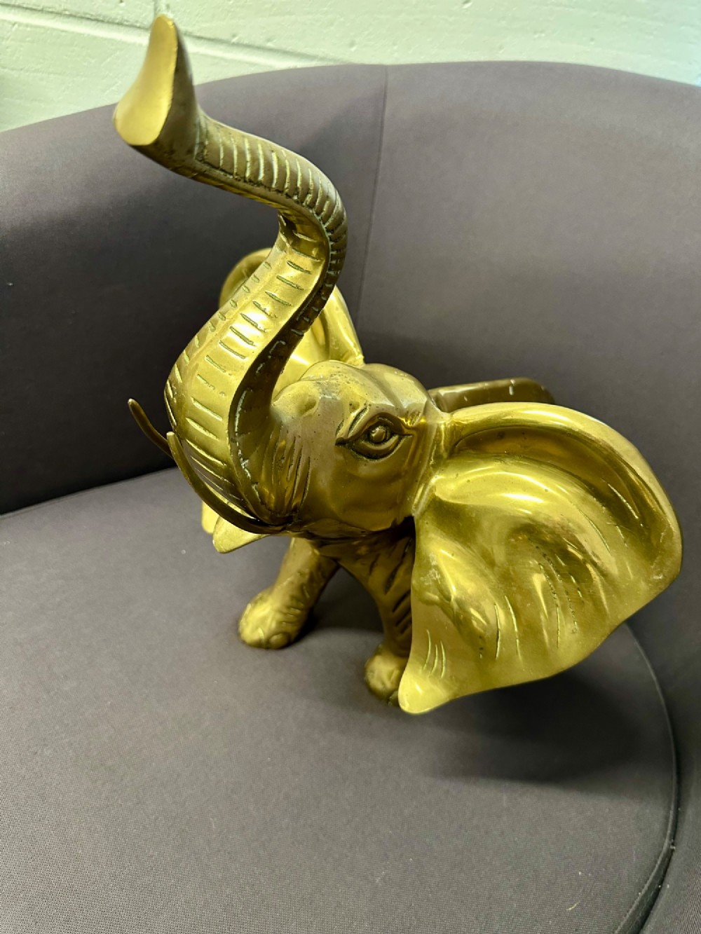 A solid brass sculpture of an elephant standing with its trunk raised up. View III