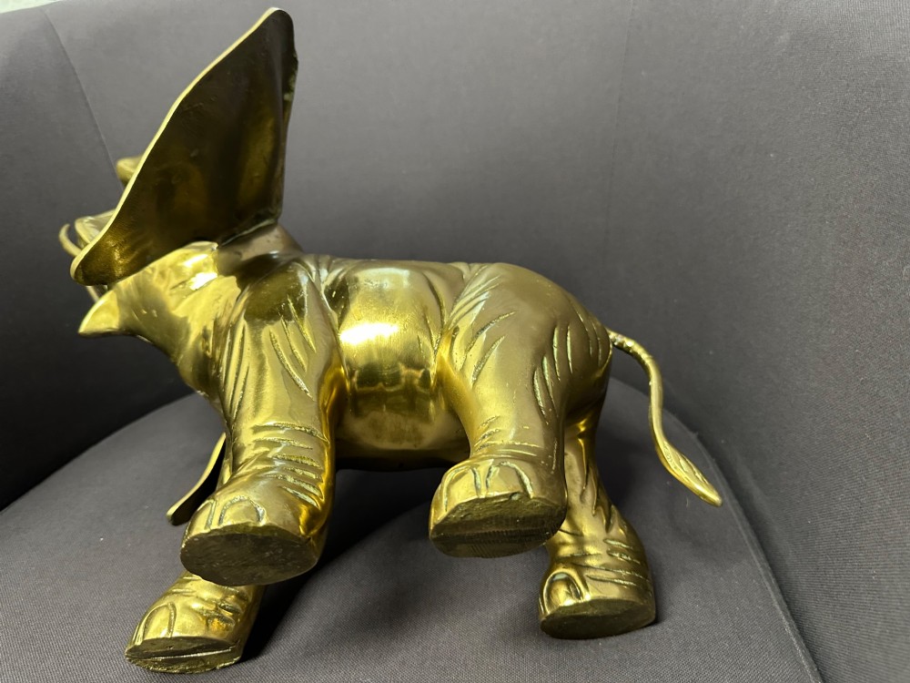 A solid brass sculpture of an elephant standing with its trunk raised up. View IV
